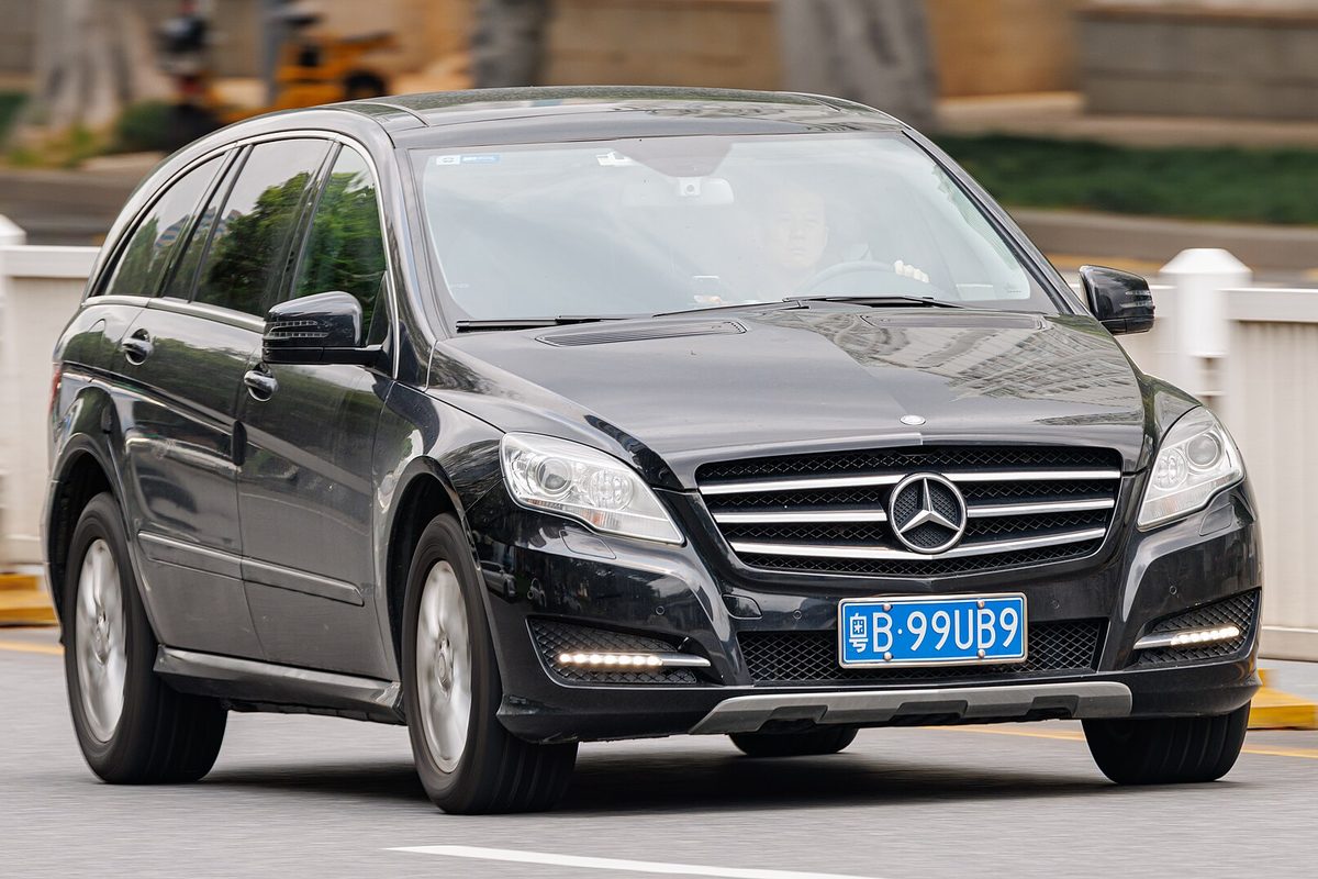 A black Mercedes-Benz R-Class with LED daytime running lights driving on a city street