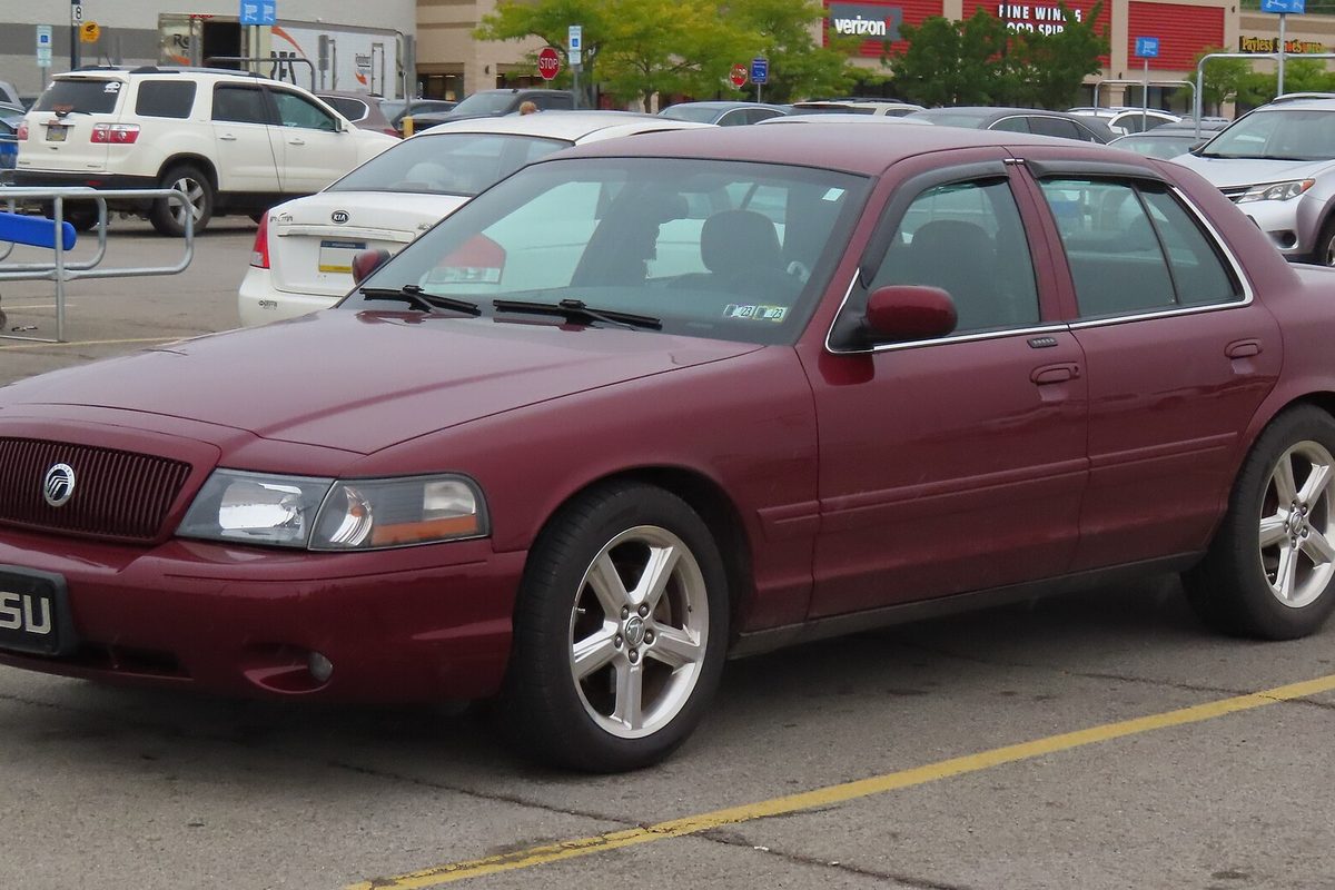 A dark red 2004 Mercury Marauder four-door sedan with silver five-spoke wheels, parked in a shopping center lot