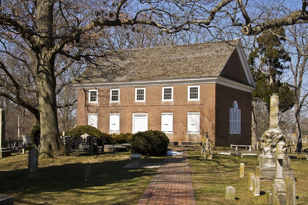 Old St. Anne's Church in Middletown, a red-brick colonial church with white shutters, a brick path and old gravestones under bare trees