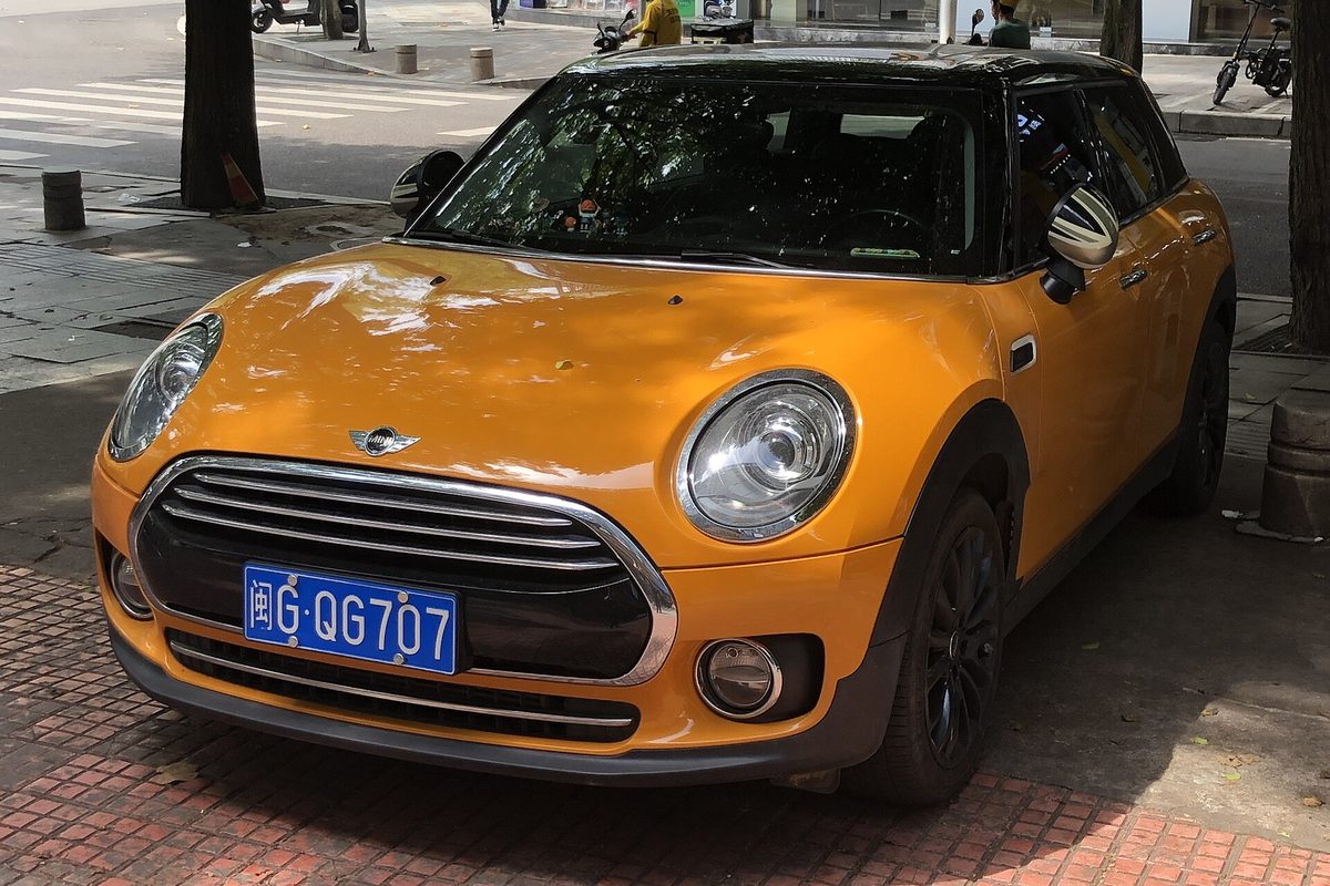 An orange second-generation MINI Clubman parked on a red brick sidewalk, seen from the front