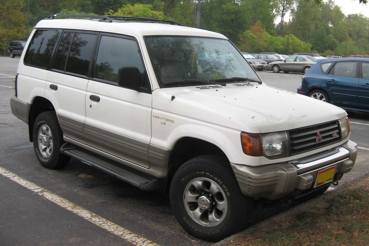 A white Mitsubishi Montero LS SUV with two-tone lower trim and side steps, parked in a lot