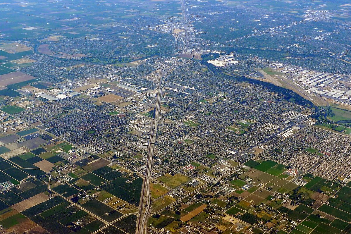 Aerial view of Modesto and Ceres, with a straight freeway cutting north through the grid of streets and green farm fields in the foreground