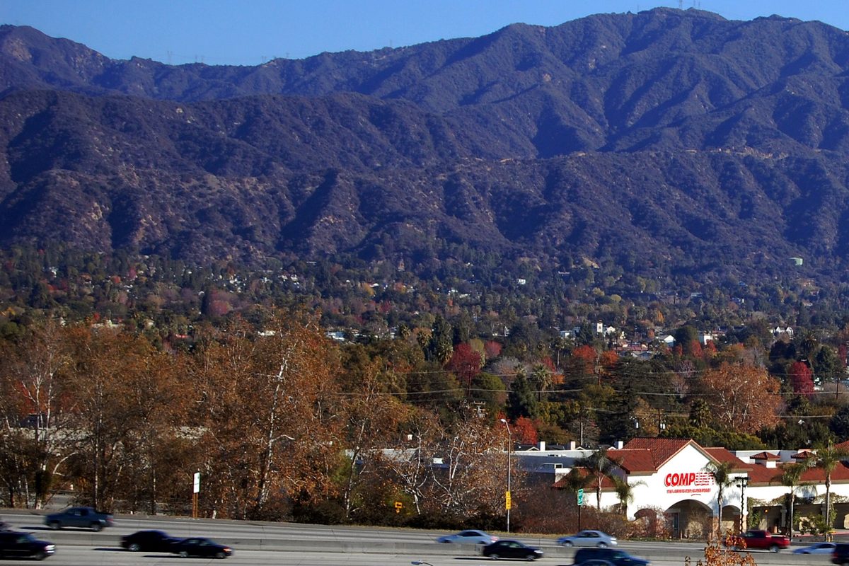 Traffic on Interstate 210 in Monrovia below the San Gabriel Mountains, with autumn trees along the freeway