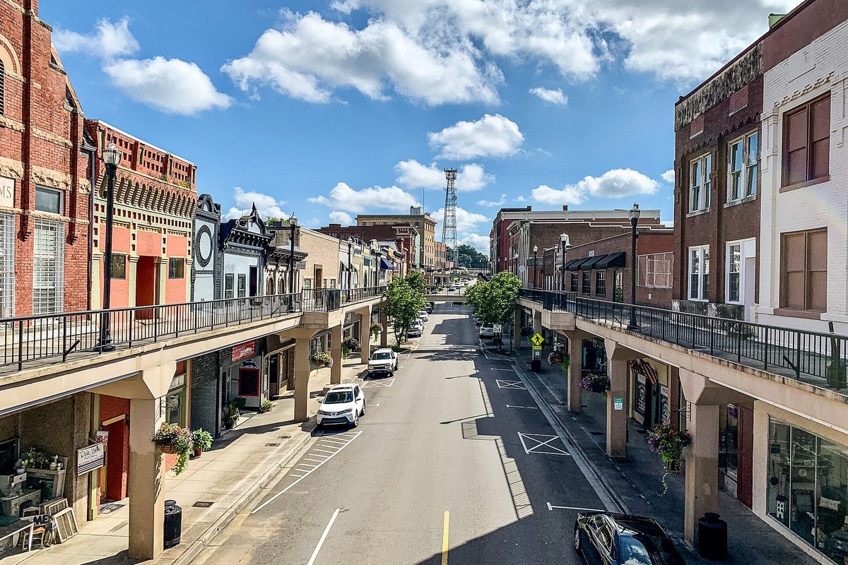 Downtown Morristown's Main Street seen from an elevated walkway, with second-story sidewalks running along both rows of brick storefronts under a blue sky