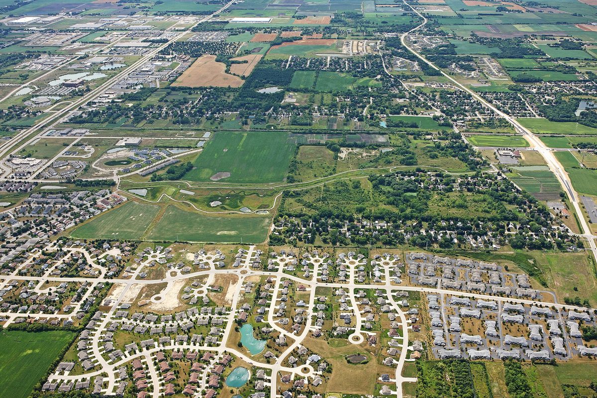 Aerial view of Mount Pleasant showing curving subdivision streets, two small ponds, open fields and a highway running through farmland