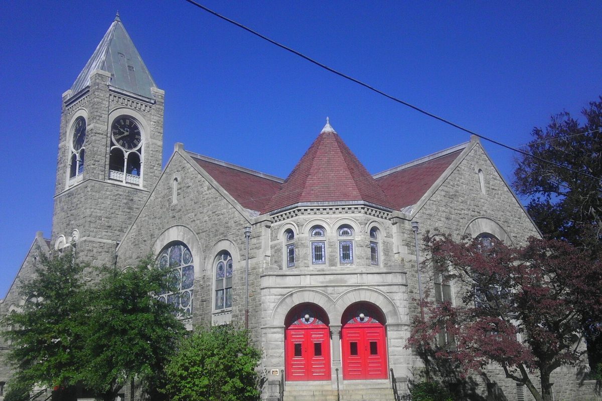 First United Methodist Church in Mount Vernon, a gray stone church with a clock tower, a red-tiled roof and red double doors under a deep blue sky