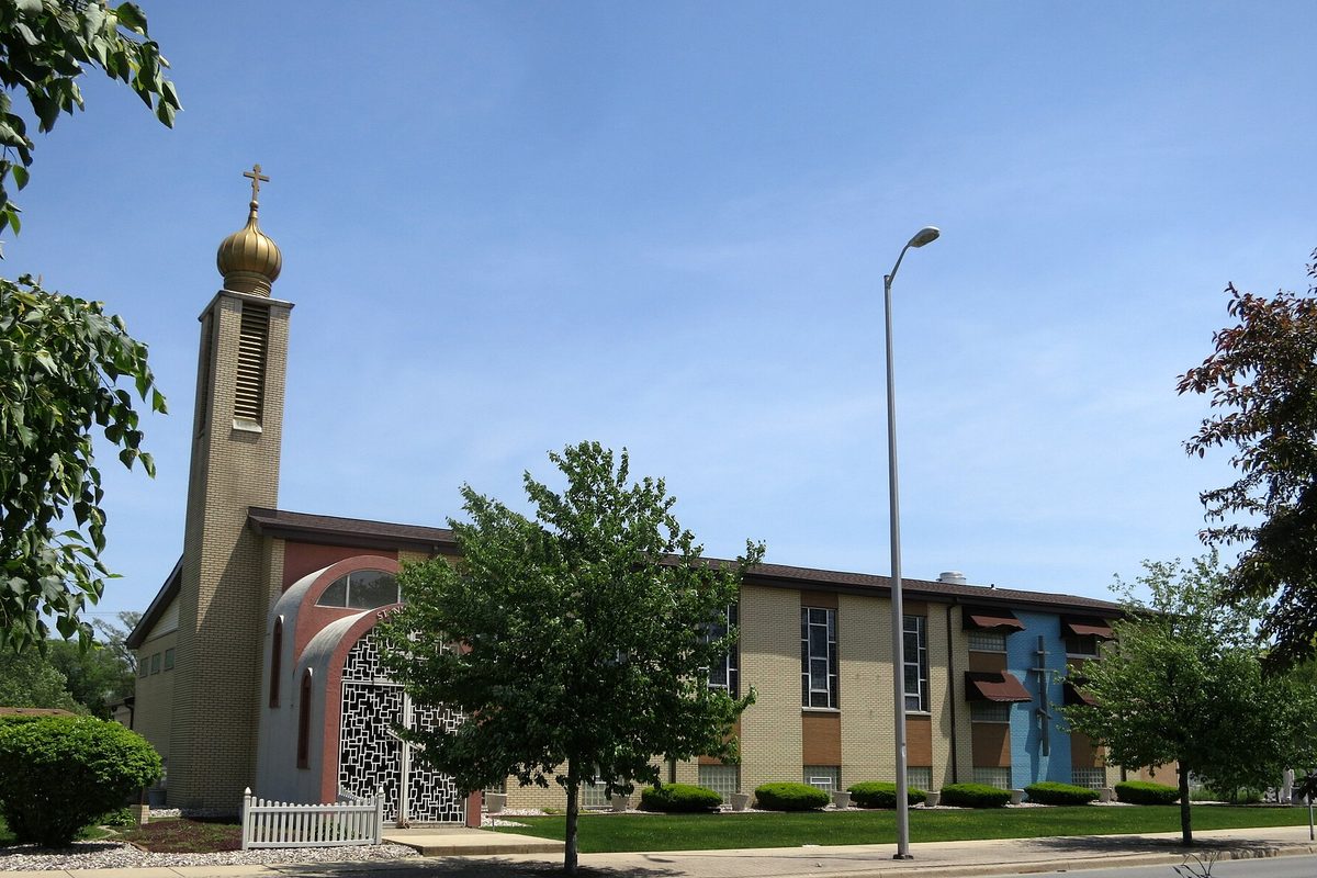 Saint Nicholas Byzantine Catholic church in Munster, a tan brick building with a bell tower topped by a gold onion dome, behind green trees