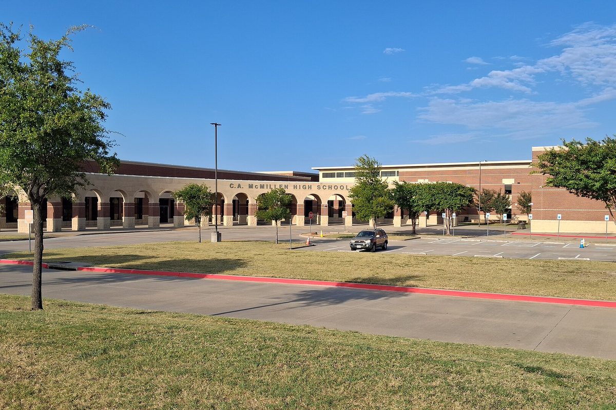 C.A. McMillen High School in Murphy, a long brick and tan building with arched walkways, behind a mowed lawn, young trees and a parking lot