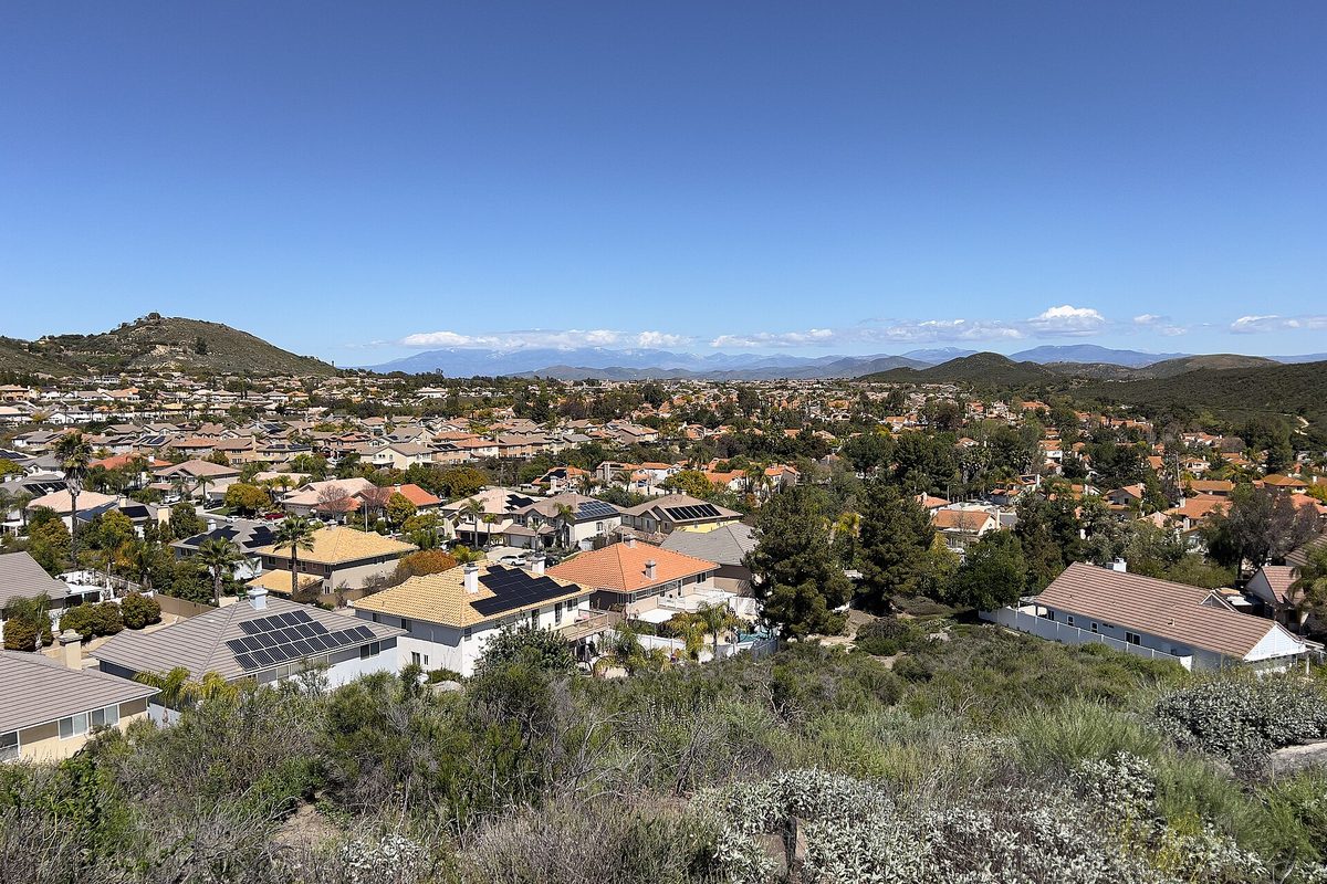 View from Falcons View Park over Murrieta's red tile roofs, some with solar panels, across a valley of homes to green hills and distant mountains