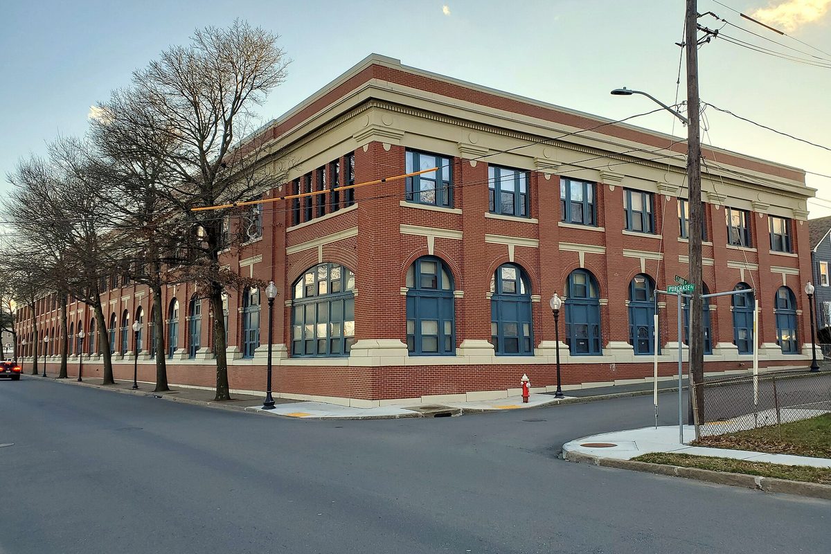 The restored red-brick former Union Street Railway carbarn on Purchase Street in New Bedford, with tall arched blue-framed windows and bare street trees