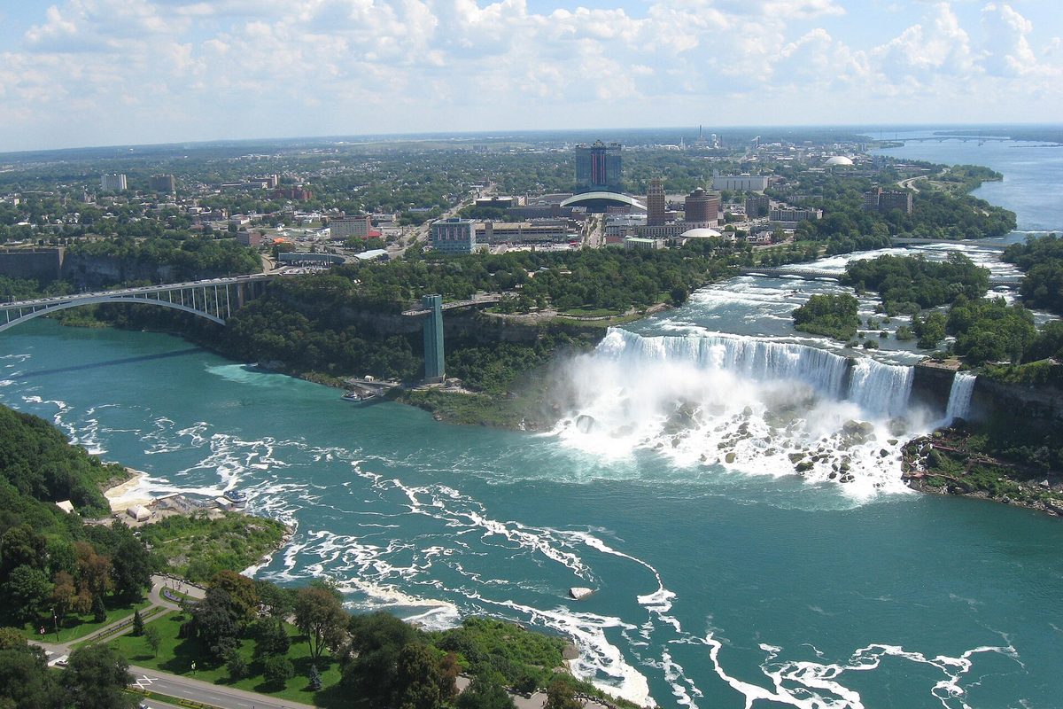 The American Falls and Bridal Veil Fall pouring into the Niagara River, with the Rainbow Bridge at left and the city of Niagara Falls, New York, beyond