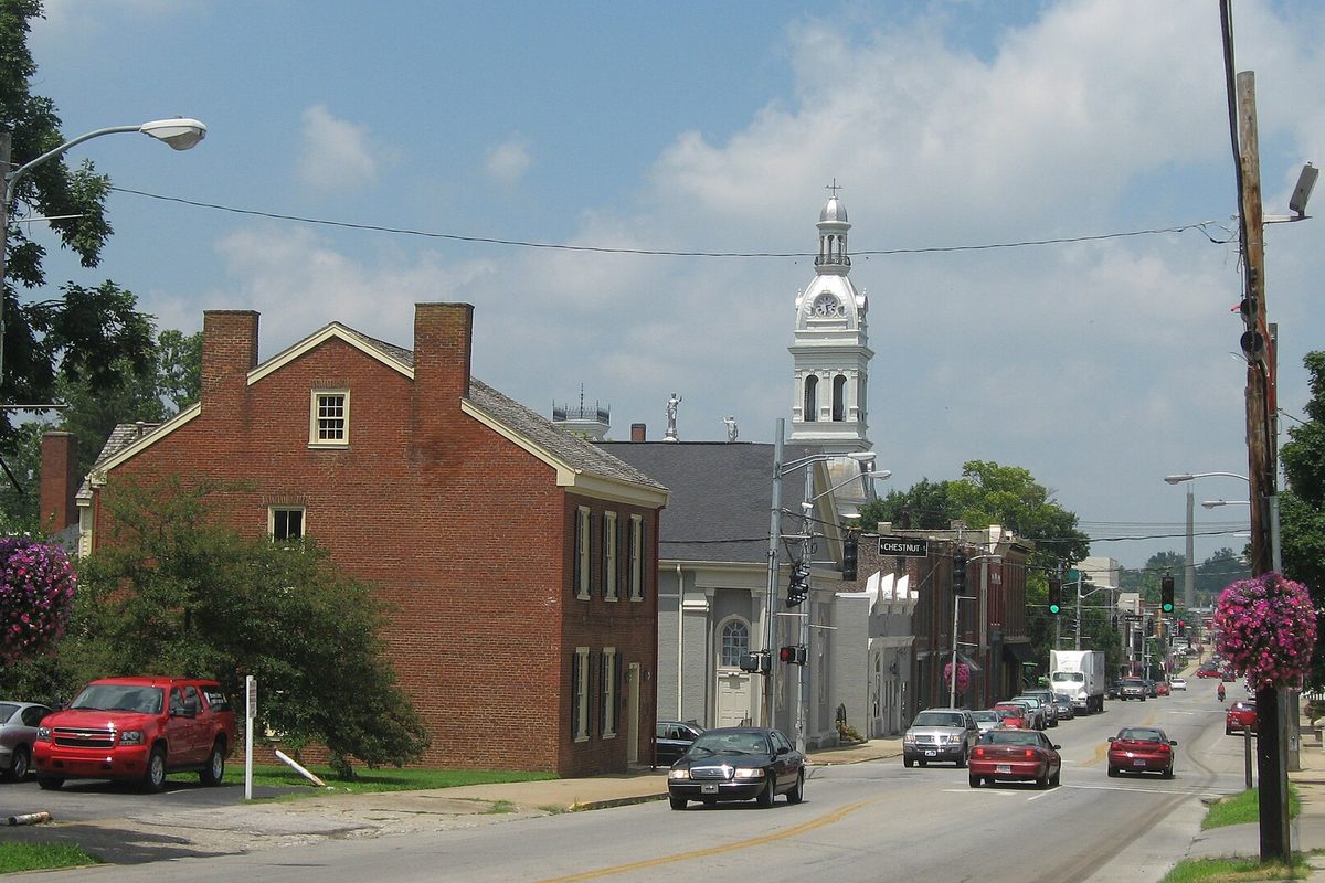 Looking north up Main Street in downtown Nicholasville, a red brick house on the left and a white clock tower rising above the storefronts
