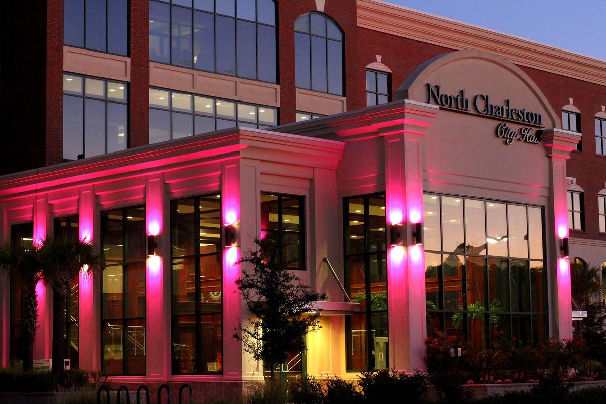 North Charleston City Hall at dusk, its columned glass entrance lit bright pink