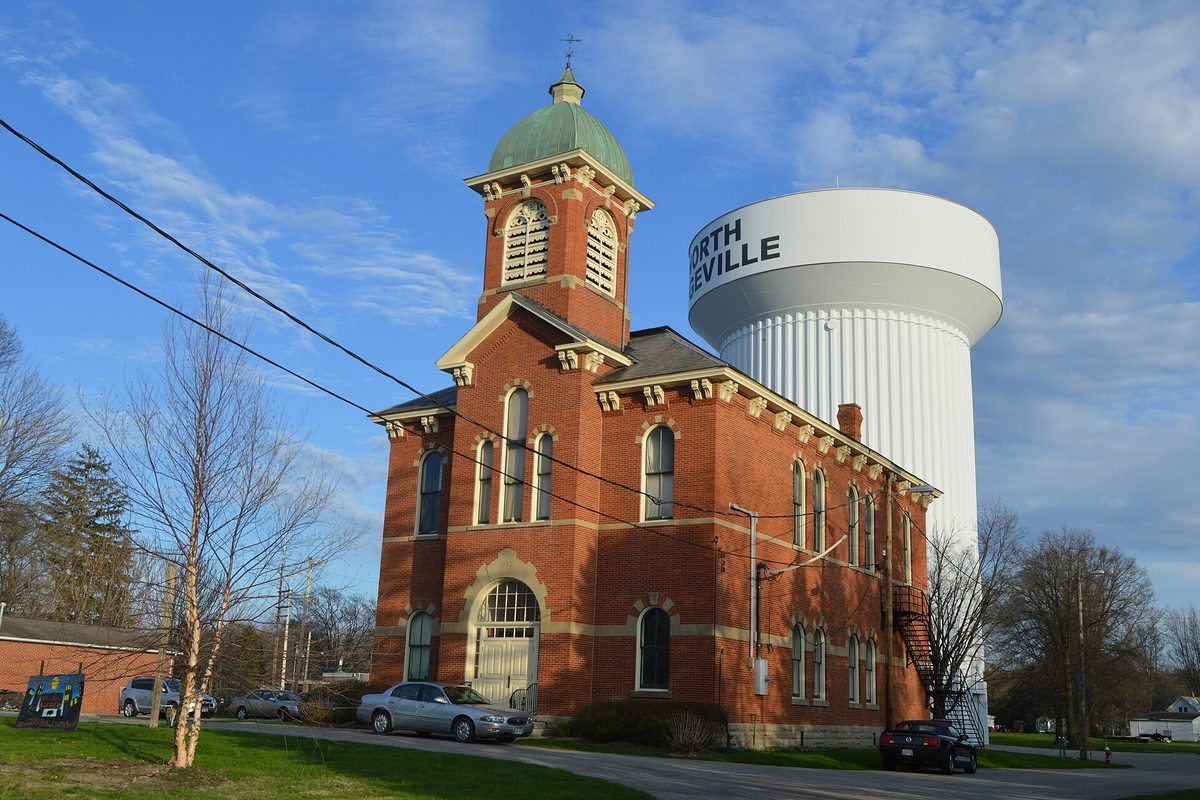 North Ridgeville's old brick city hall with a green-domed cupola and arched windows, the white city water tower rising behind it