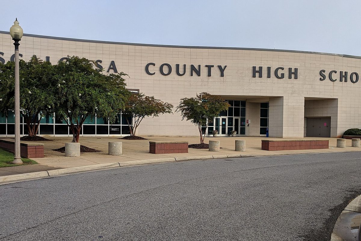 The tan brick front of Tuscaloosa County High School in Northport, with young trees and planters along the entrance walk
