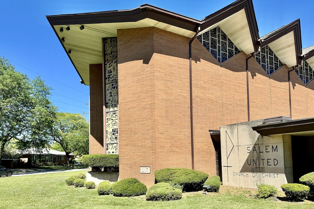 The modern brick Salem United Church of Christ in Oak Lawn, with tall stained-glass windows under a peaked roofline, trimmed shrubs and a lawn in front