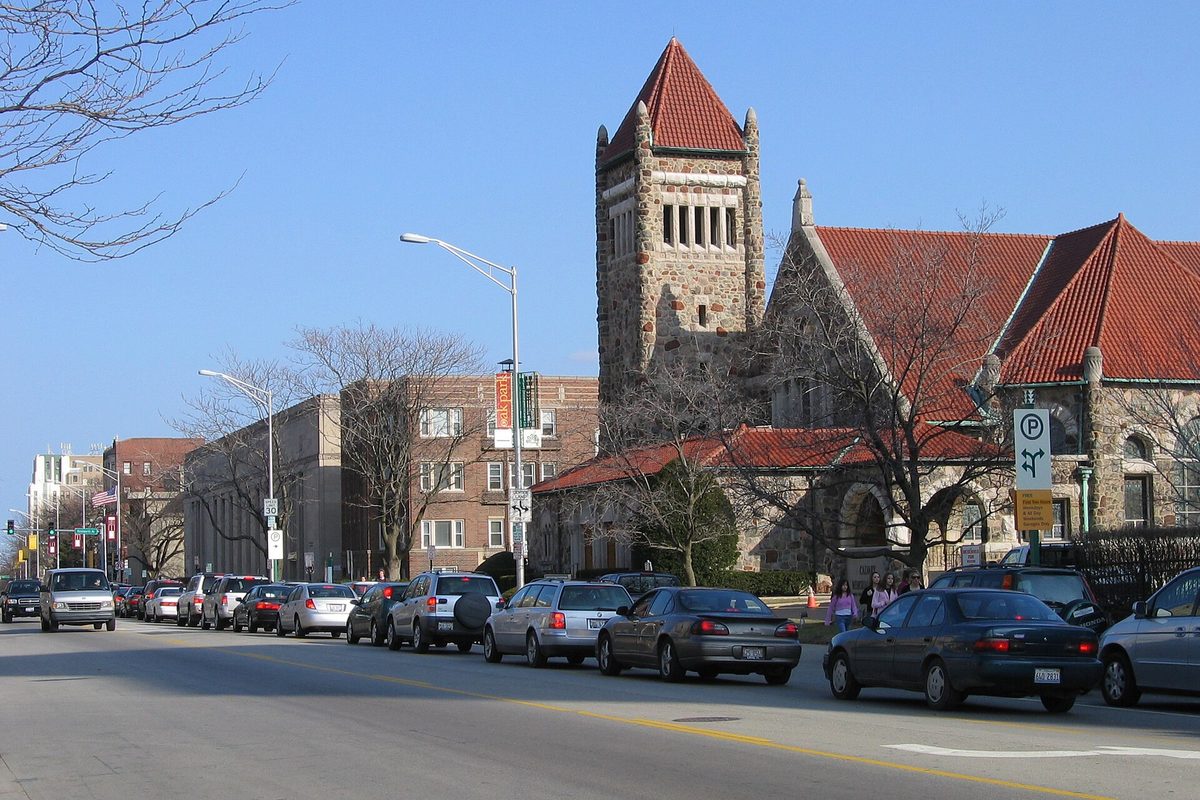 Lake Street in Oak Park on a clear day, with cars parked along the curb in front of the stone tower and red tile roofs of Calvary Memorial Church