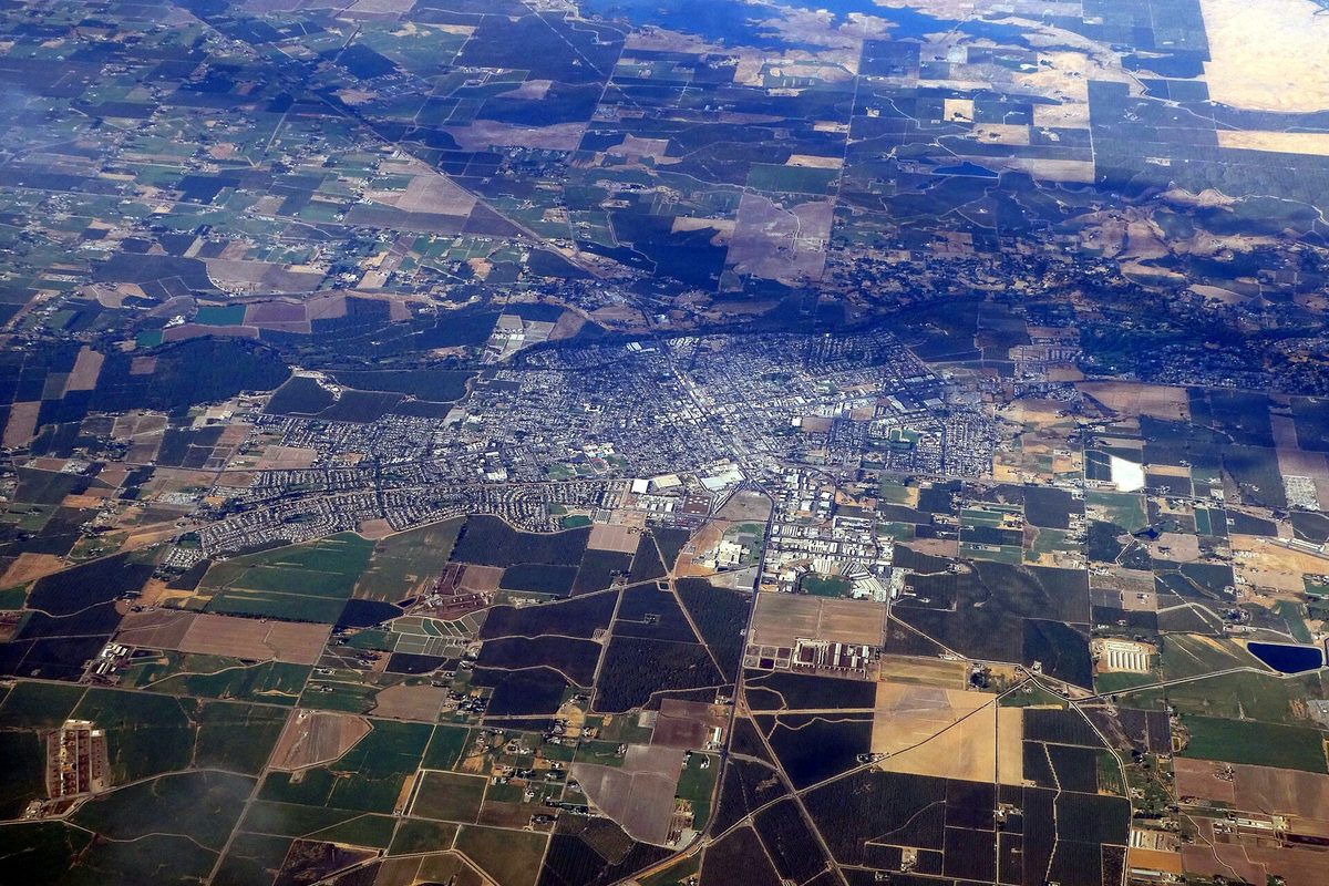 Aerial view of Oakdale's street grid in the middle of a patchwork of farm fields, with dry hills on the horizon