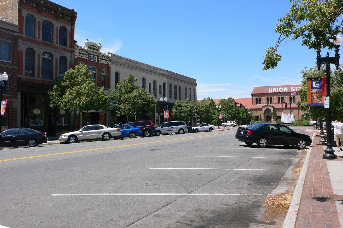 Parked cars along Historic 25th Street in Ogden, with old brick storefronts on the left and Union Station at the far end of the street