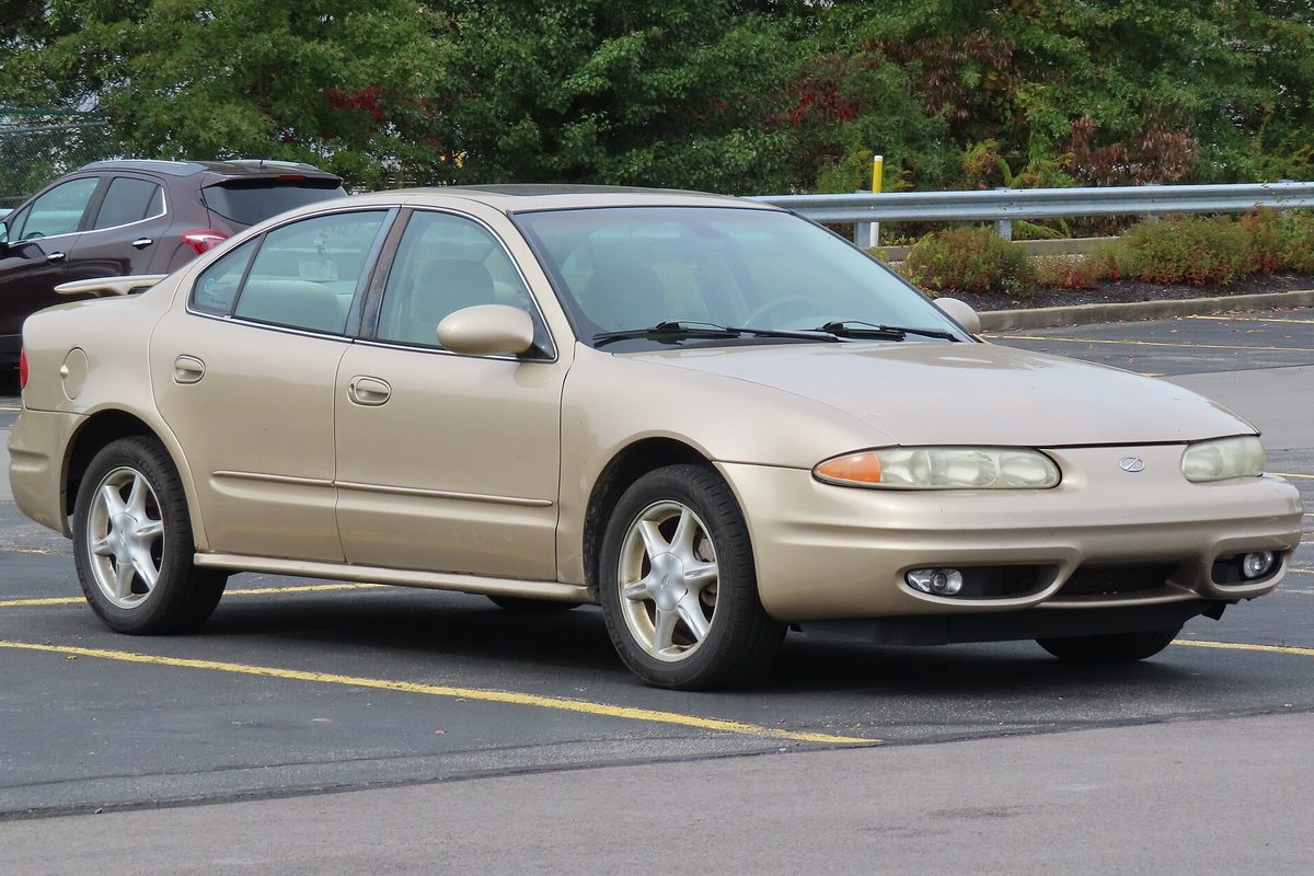 A tan 2002 Oldsmobile Alero sedan parked in a lot, seen from the front right