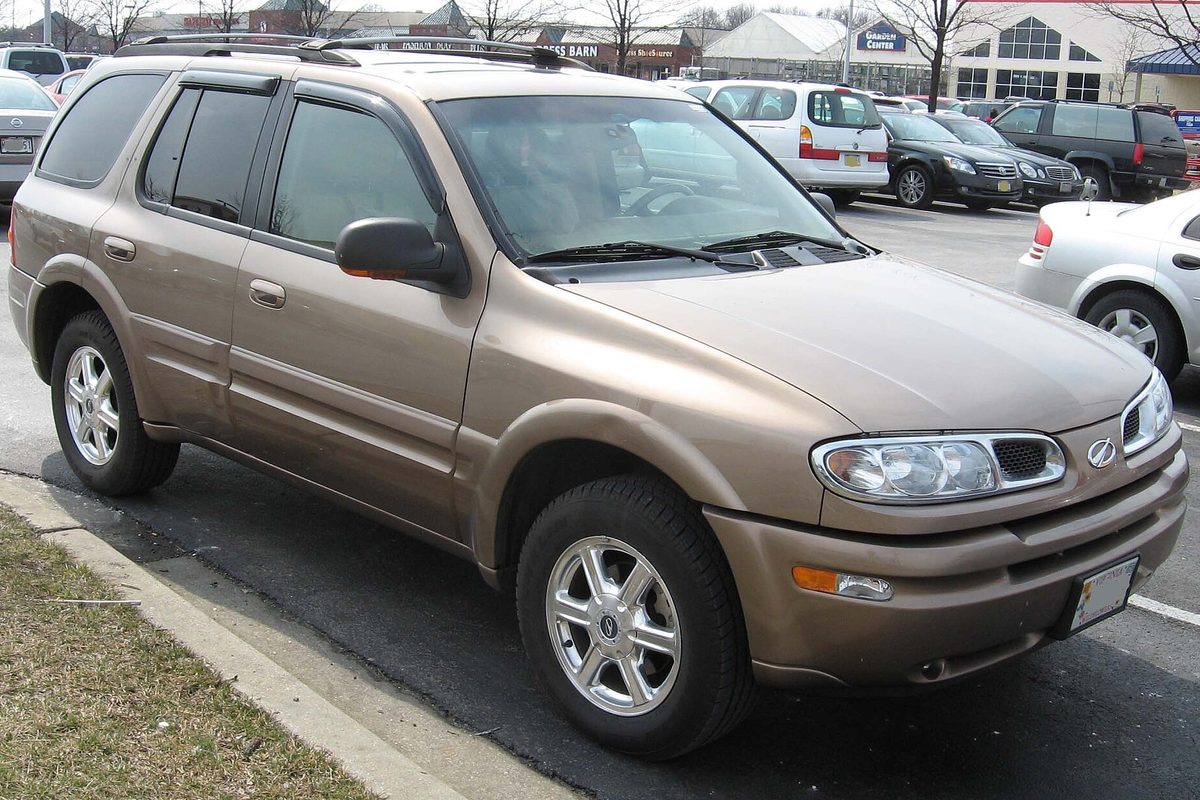 A bronze 2002-2004 Oldsmobile Bravada SUV in a shopping center parking lot, seen from the front right
