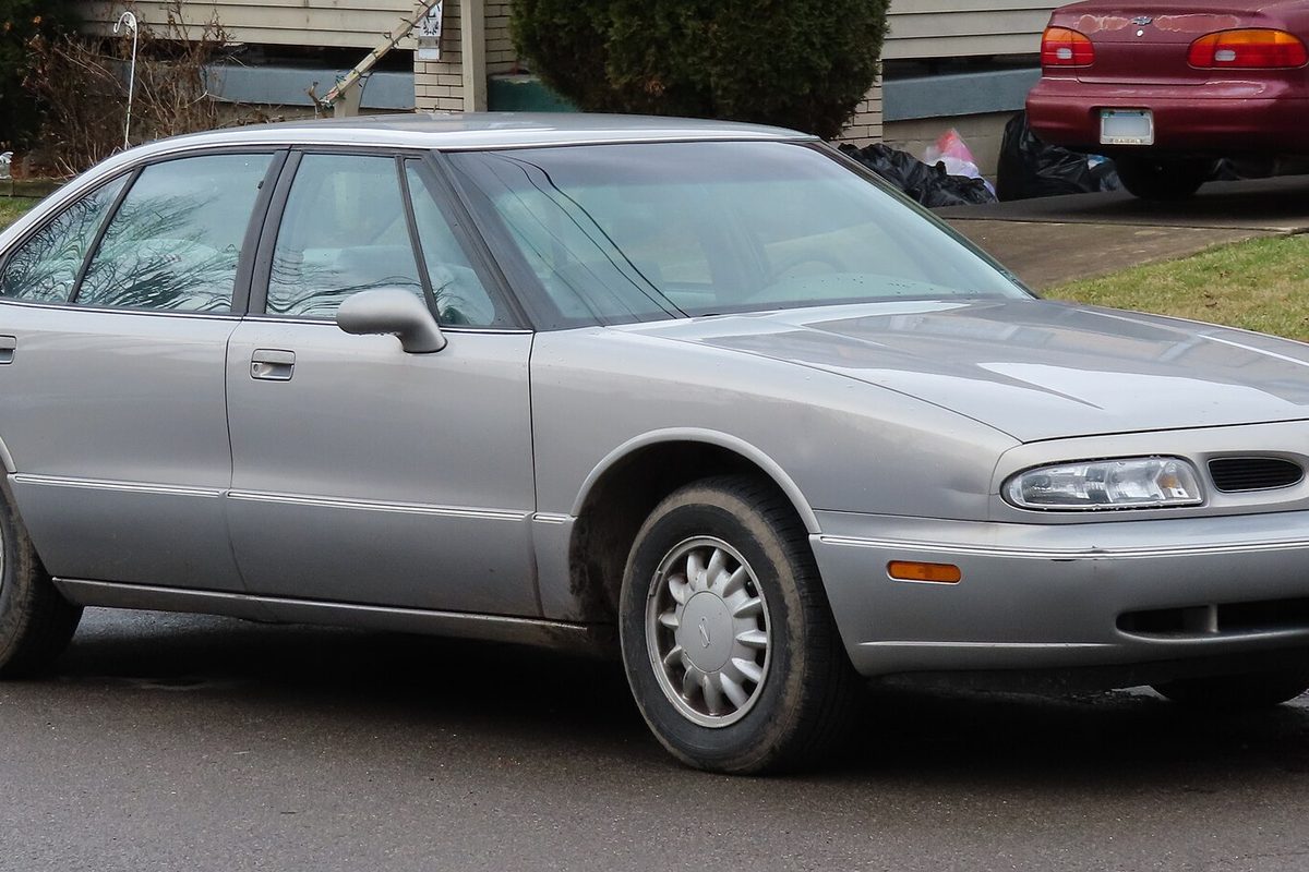 A silver 1998 Oldsmobile Eighty-Eight sedan parked on a residential street, seen from the front right