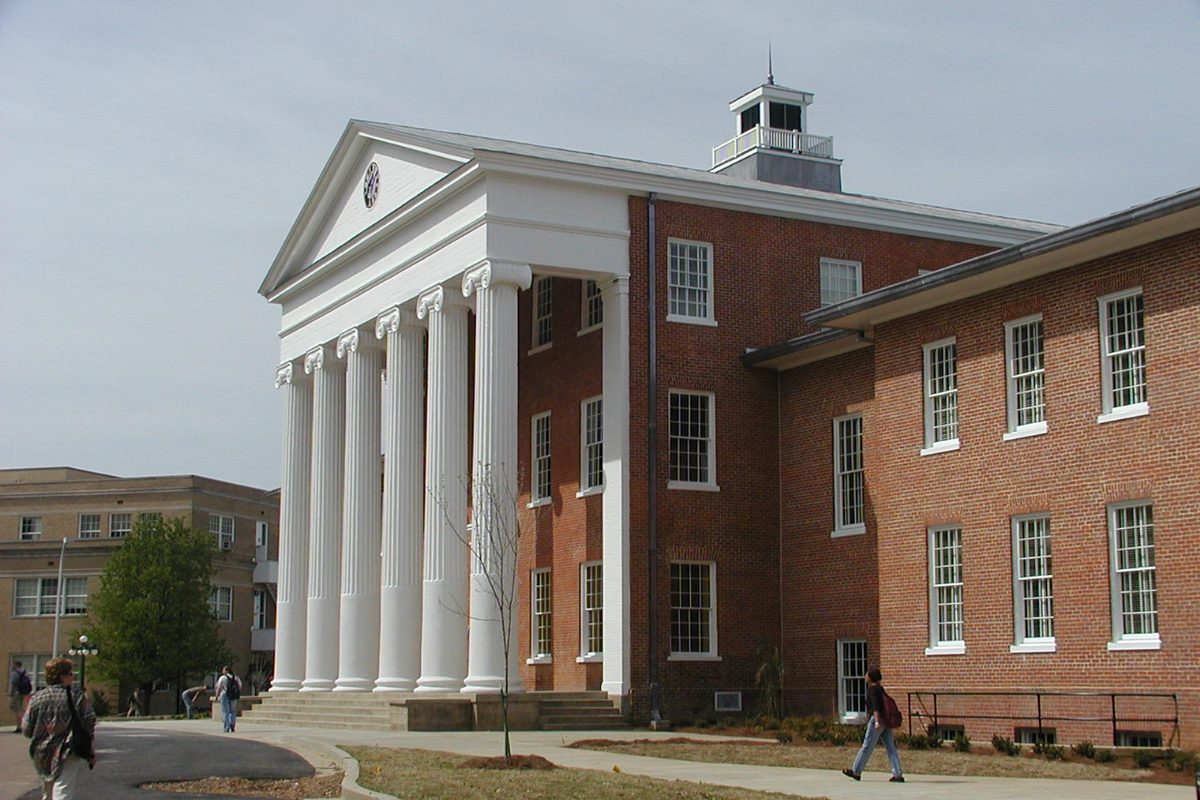 The Lyceum at the University of Mississippi, a red brick building with six white columns, as people walk past