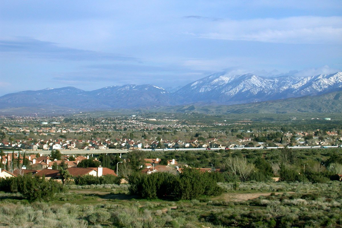 Palmdale homes spread across the valley floor beyond desert scrub, with snow-capped mountains on the horizon