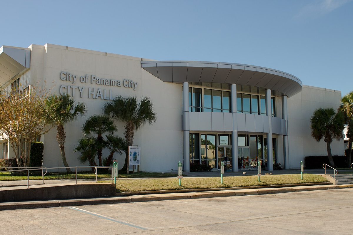 Panama City City Hall, a white modern building with its name in raised letters, a curved glass entrance and palm trees along the front lawn