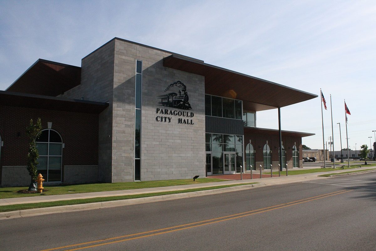 Paragould City Hall, a modern stone and brick building with a steam locomotive emblem above its name and flags out front