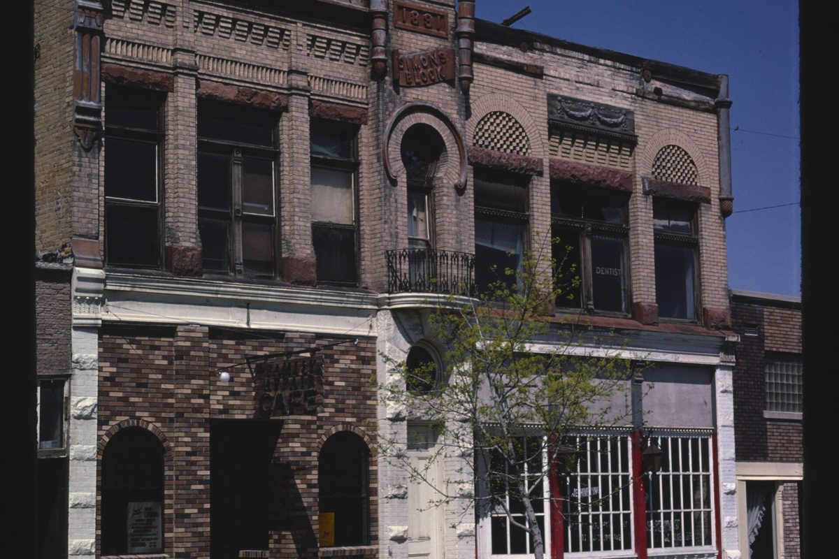 The Simons Block on Payson's Main Street, an ornate two-story brick building with arched upper windows, a small iron balcony and a young tree in front