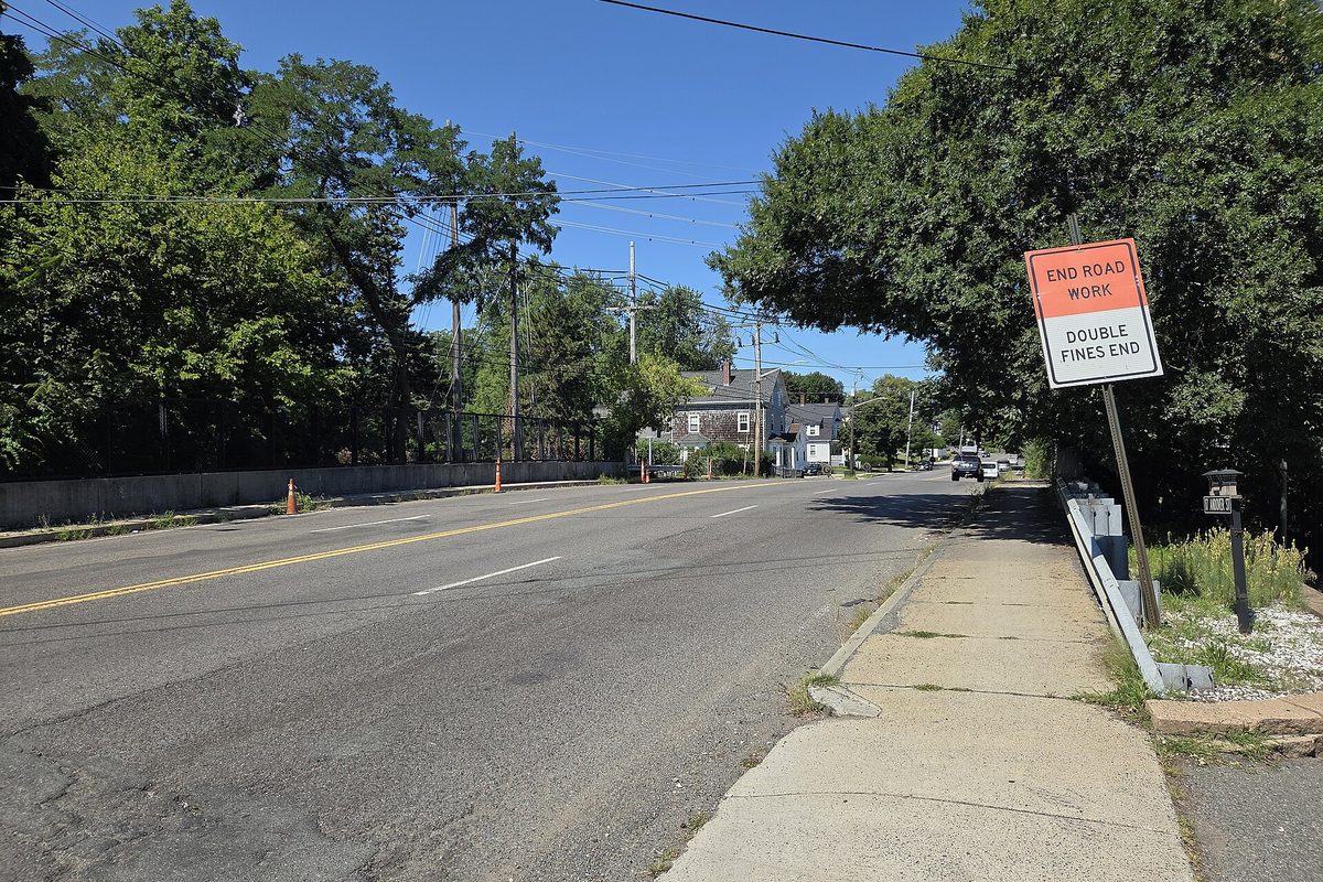 A two-lane road under summer trees in Peabody, with an orange sign reading End Road Work, Double Fines End beside the sidewalk