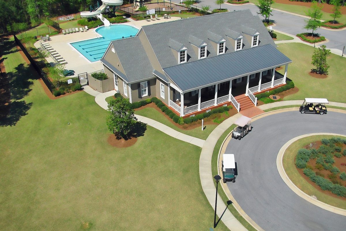 Aerial view of the Centennial subdivision clubhouse in Peachtree City, with a swimming pool and water slide beside it and golf carts parked on a circular drive