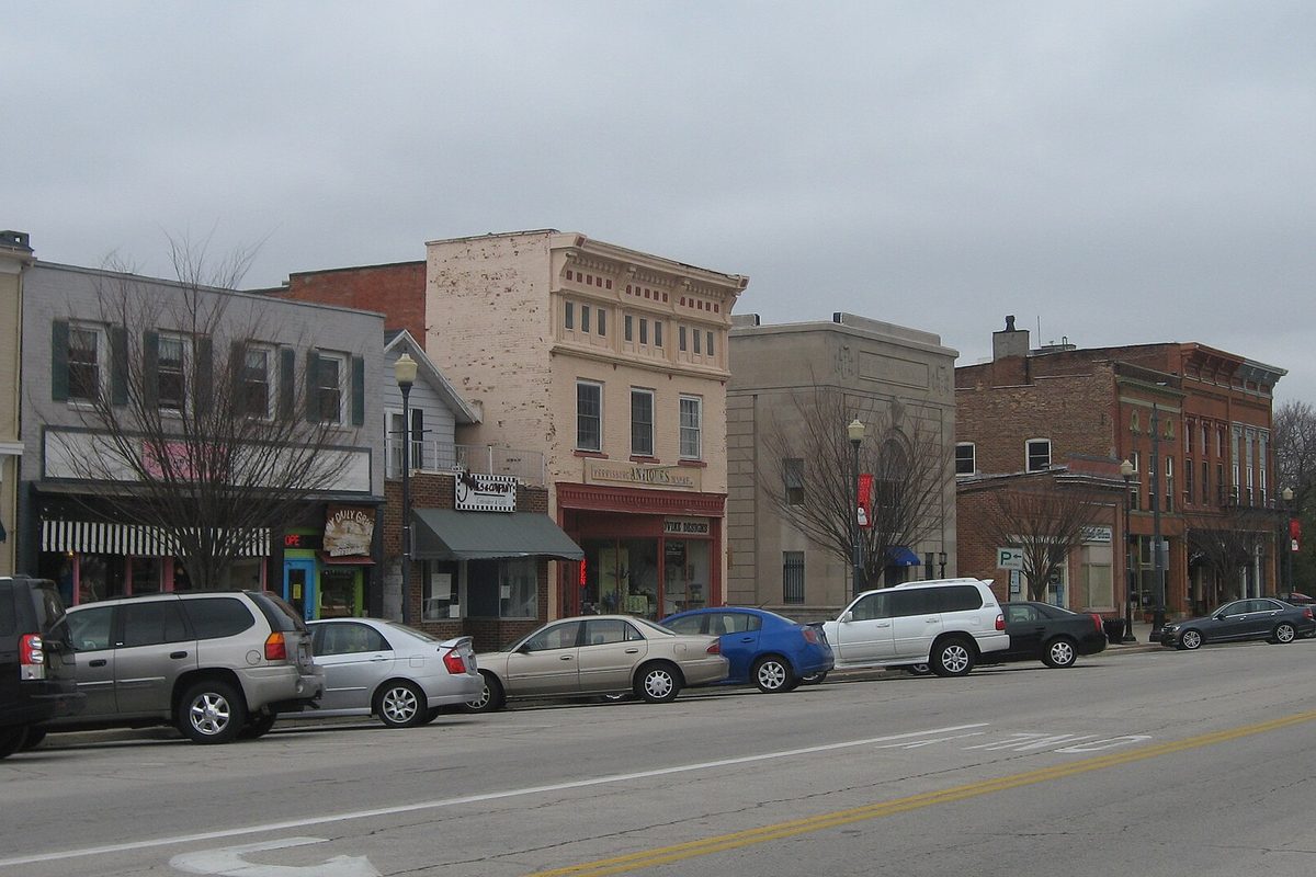 Two- and three-story brick storefronts along Louisiana Avenue in downtown Perrysburg's historic district, with cars parked at the curb under a gray sky