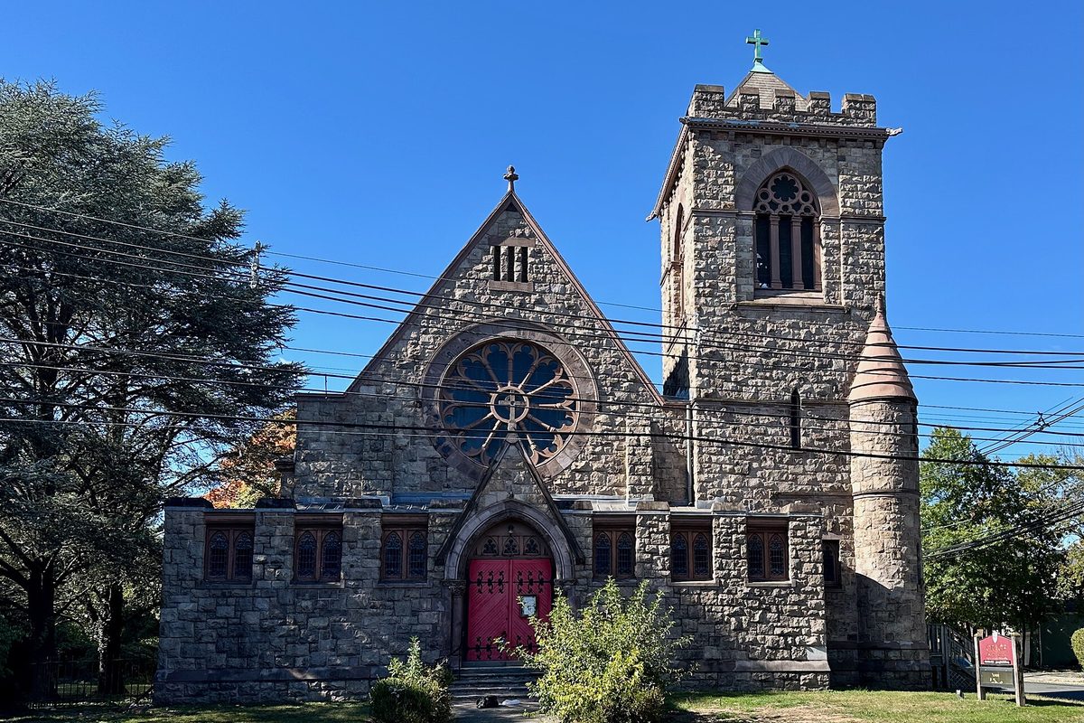 Grace Episcopal Church in Plainfield seen from 7th Street, a gray stone church with a round rose window, red doors and a square bell tower
