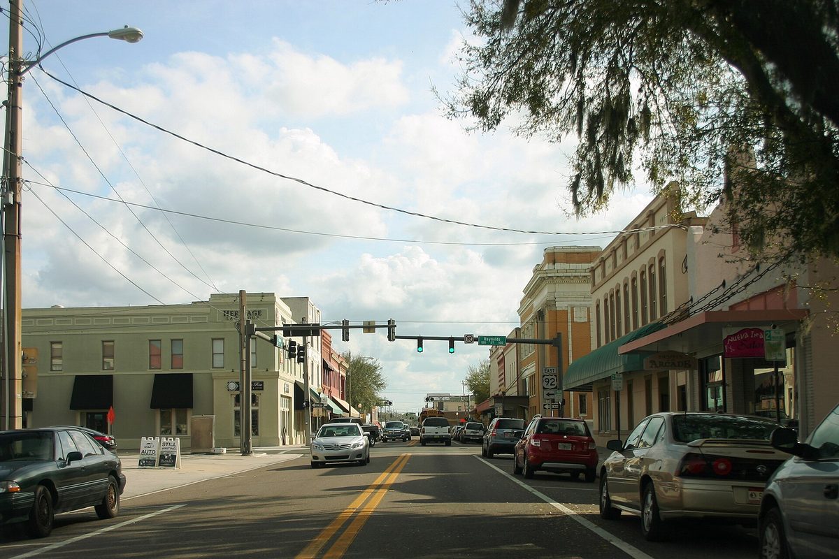 Downtown Plant City on westbound US 92, with brick storefronts, a traffic light over the road and cars parked along the curb