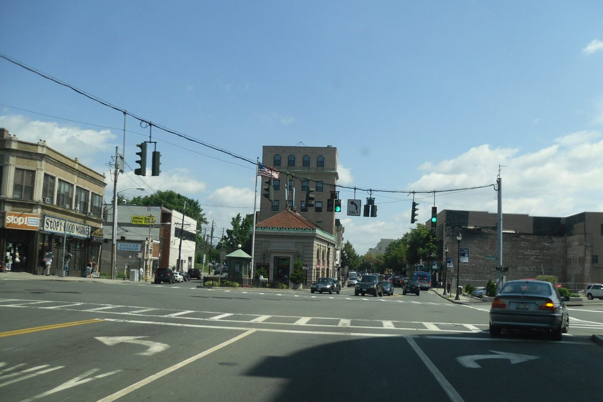 U.S. Route 1 through downtown Port Chester, an intersection with traffic lights, storefronts, a small domed building and an older office tower