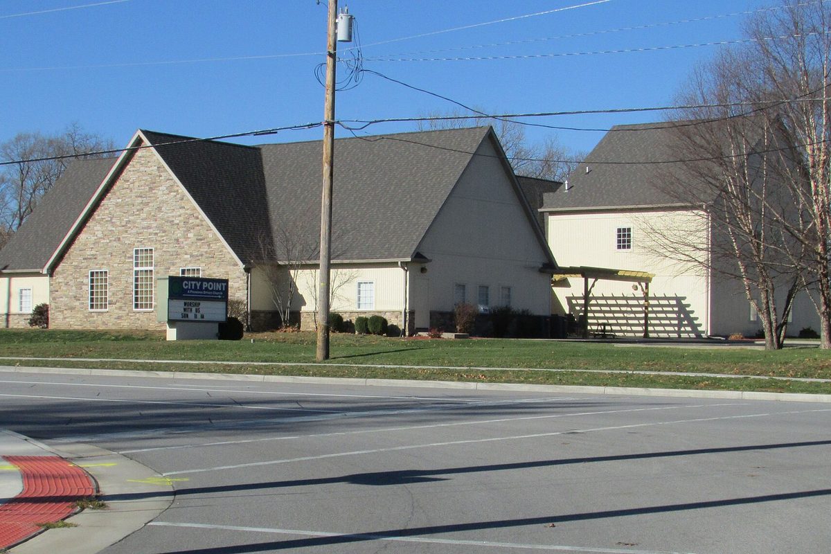 City Point Church on Central Avenue in Portage, a stone and cream-sided building with gabled roofs and a roadside sign, under a clear blue sky