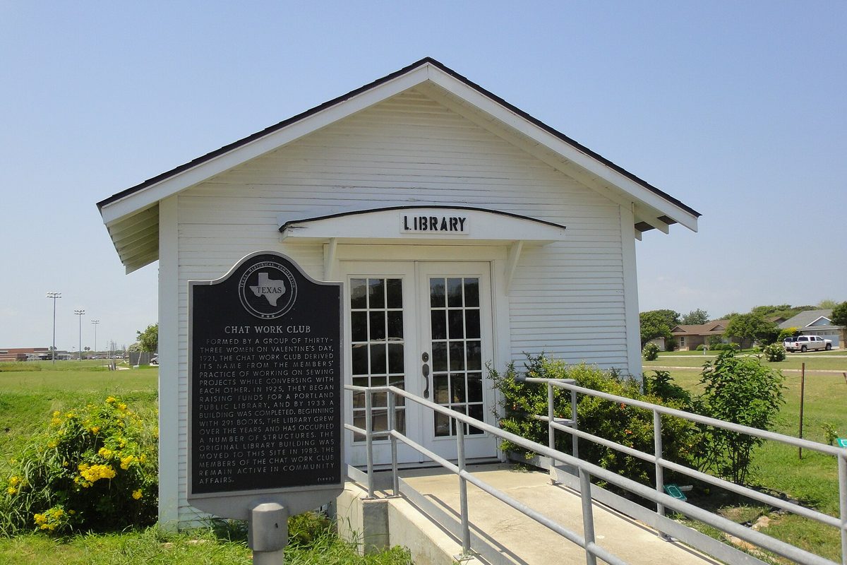 Portland's old library, a small white wooden building with a LIBRARY sign over glass doors, a Texas historical marker and a railed ramp in front