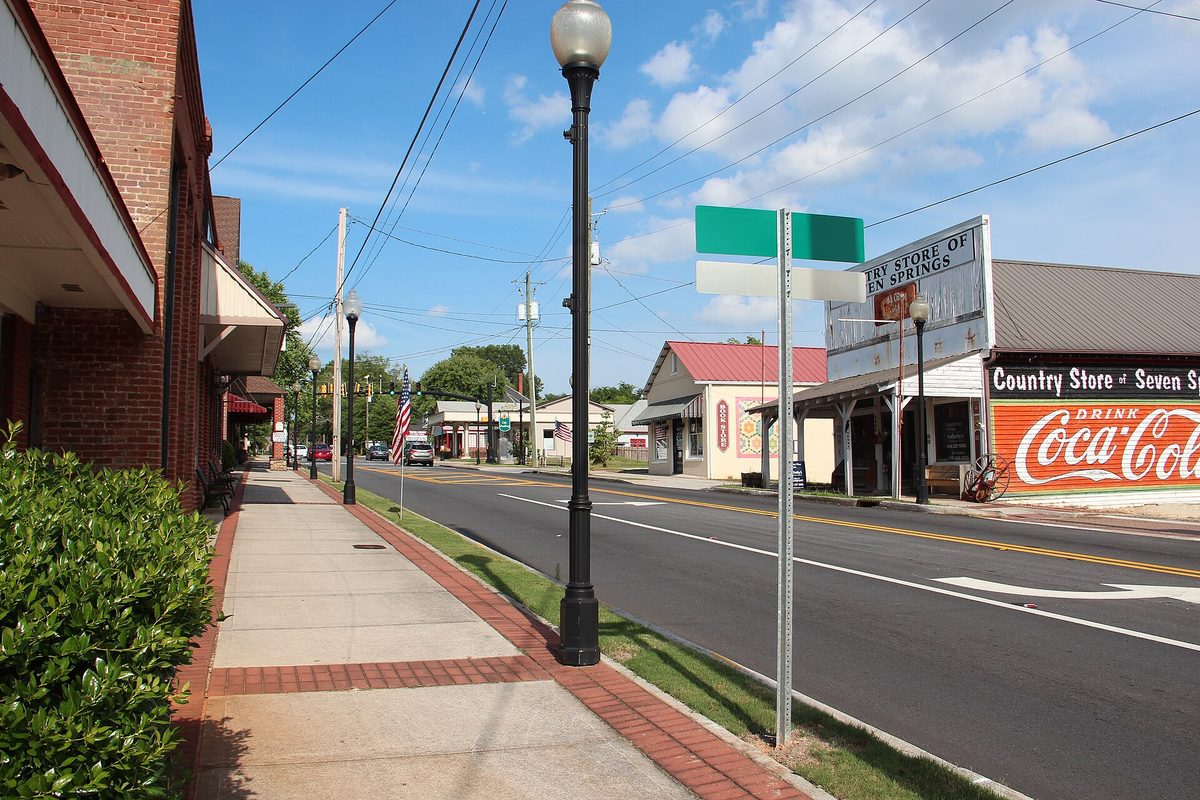 Marietta Street in downtown Powder Springs, with a brick sidewalk, black lamp posts, a street sign and a country store painted with a Coca-Cola mural