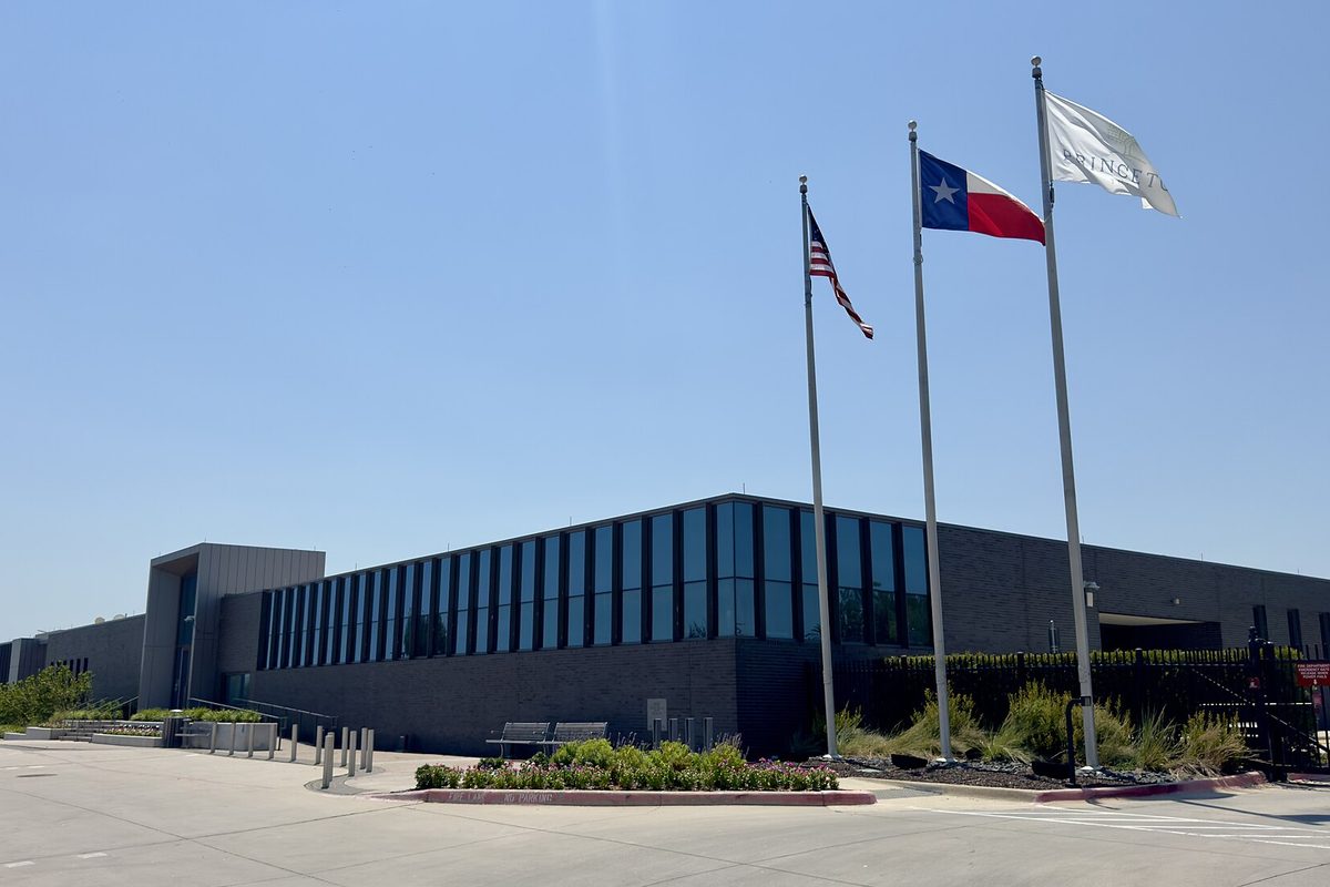 Princeton City Hall and Municipal Center, a long low building with dark glass, behind three flagpoles flying the U.S., Texas and city flags