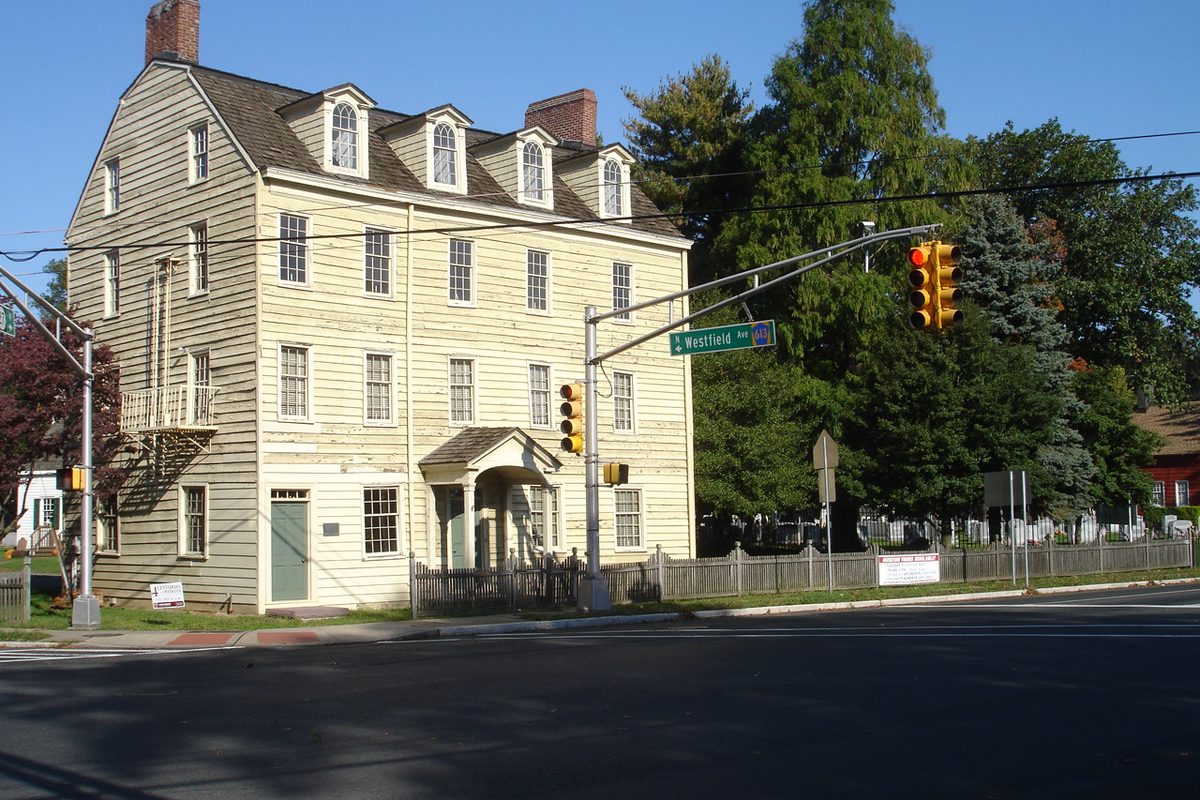 The pale yellow, three-story Merchants and Drovers Tavern on a street corner, with traffic lights and a green Westfield Rd street sign on a pole in front