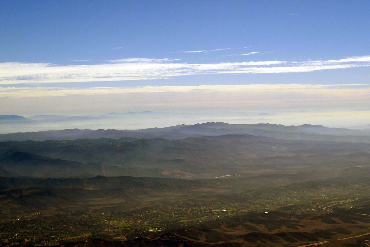 A hazy view over Rancho Santa Margarita and the ridges of the Santa Ana Mountains under a blue sky with thin clouds