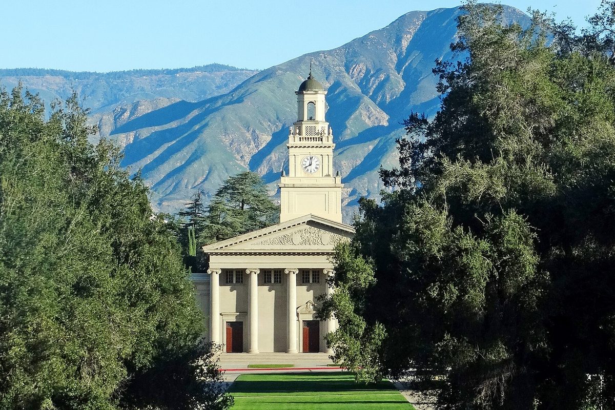 The white columned chapel with a clock tower at the University of Redlands, framed by trees, with the San Bernardino Mountains behind