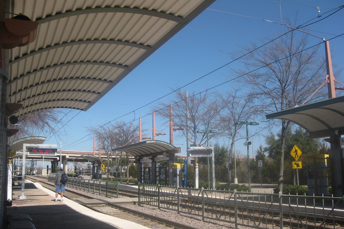 The Bush Turnpike DART light rail station in Richardson, with curved canopies over the platform, overhead wires and bare winter trees