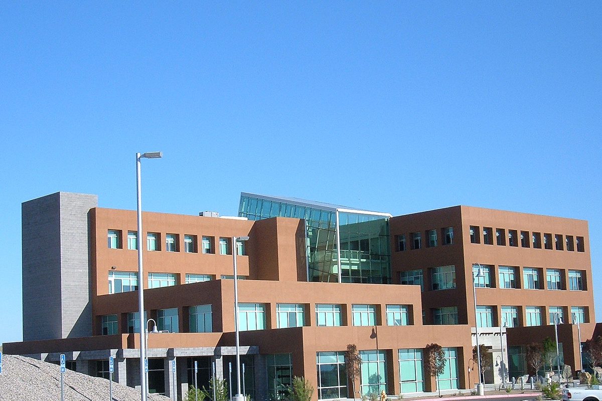 Rio Rancho City Hall, a terracotta-colored building with a glass upper section and a streetlight in front, under a clear blue sky