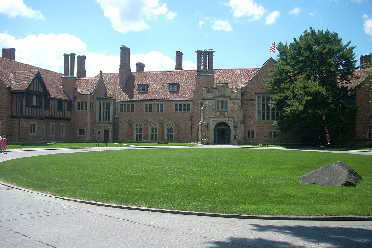 Meadow Brook Hall in Rochester Hills, a Tudor Revival brick mansion with tall chimneys and a stone entrance behind a round green lawn