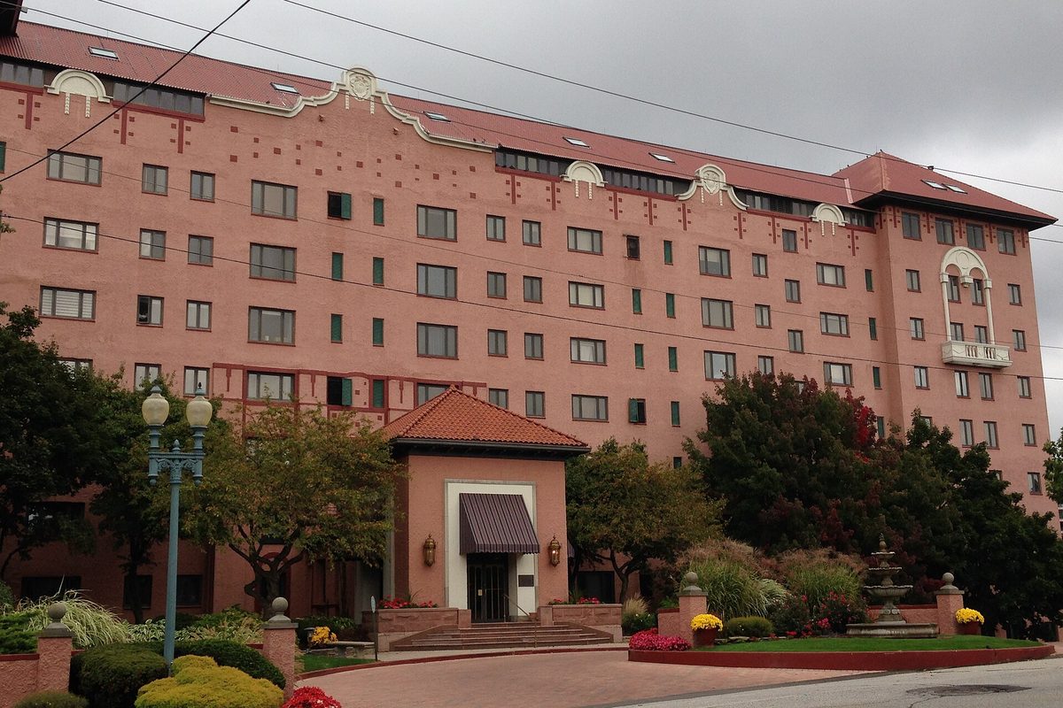 The Westlake Hotel building in Rocky River, a tall pink-stucco block with a red tile roof and ornamental gables, a canopied entrance and a drive with a fountain