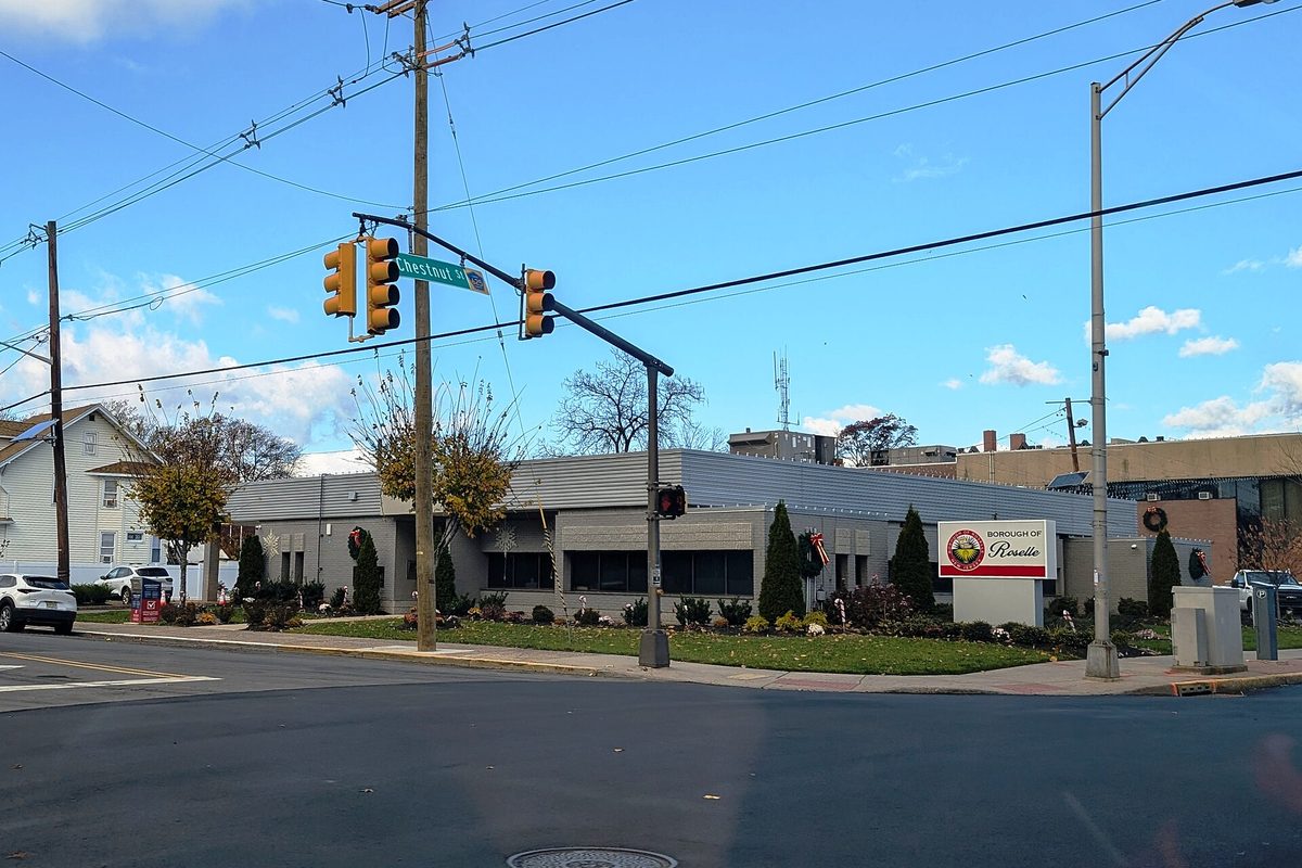 Roselle Borough Hall, a low gray building on a street corner, with traffic lights on Chestnut Street and a Borough of Roselle sign out front
