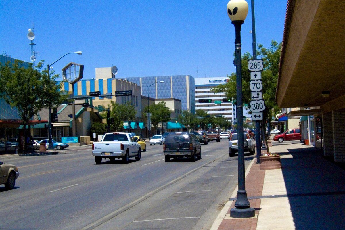 Traffic on Main Street in downtown Roswell, with a pickup truck in the lane and a lamp post on the sidewalk carrying U.S. 285, 70 and 380 route signs